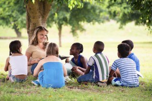 camp counselor reading a book to young students